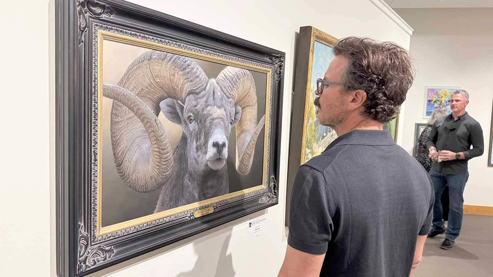A patron admires "Full Curl," an oil painting by Adam Smith, during the opening of the 45th Buffalo Bill Art Show and Sale in Cody.