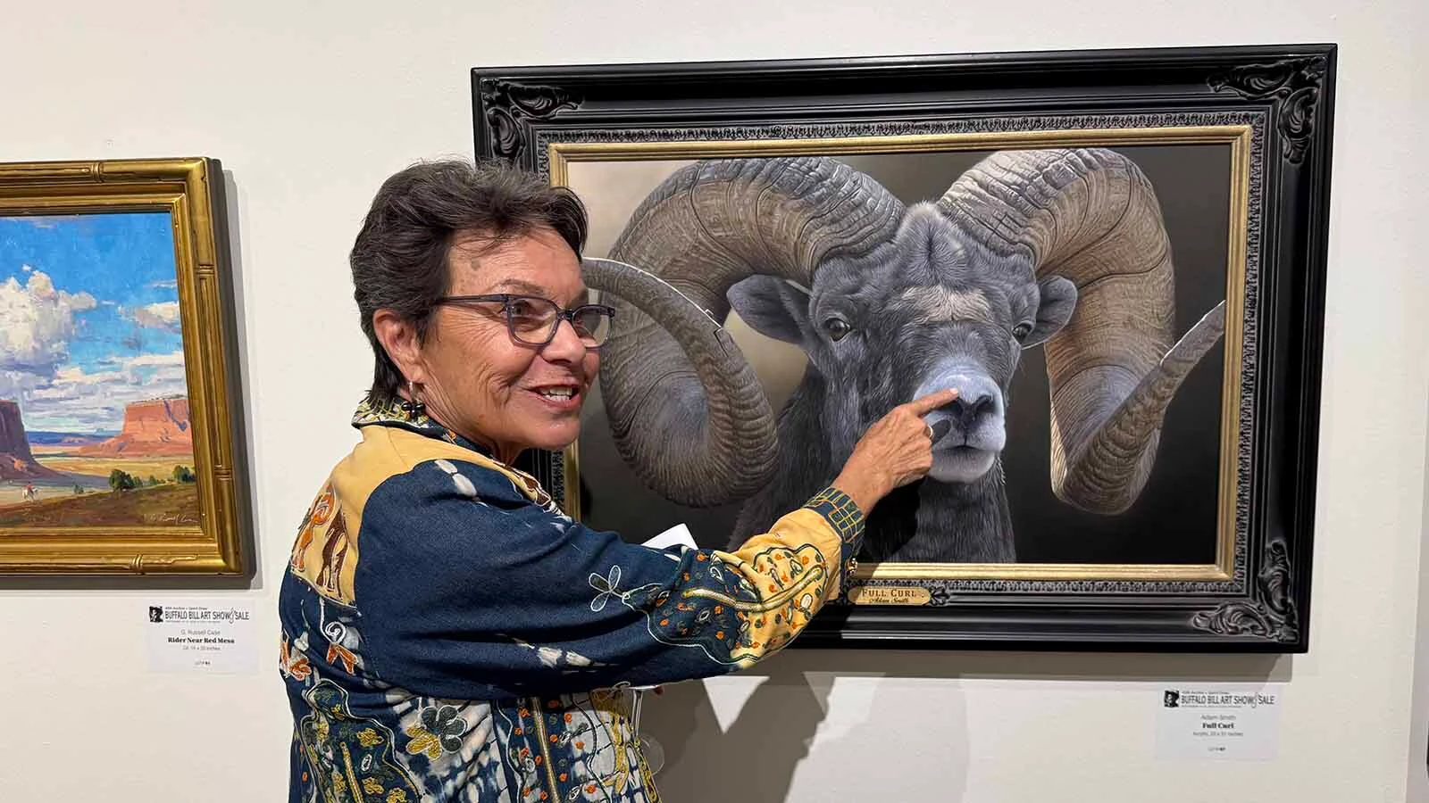 Betsy Grassby, executive director of the Steamboat Art Museum in Steamboat Springs, Colorado, fawns over the "small details" and photorealism that gave "Full Curl," an oil painting by Adam Smith, the Two-Dimensional Award for the 45th Buffalo Bill Art Show and Sale.