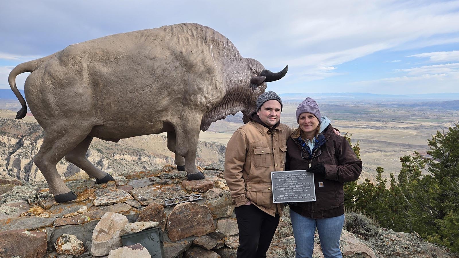 Dr. Jeremy Johnston’s son Sam (from left), and wife Amanda hold the plaque installed on the statue base in October 2025. The statue was rededicated in honor of Johnston, who passed away in June 2024.