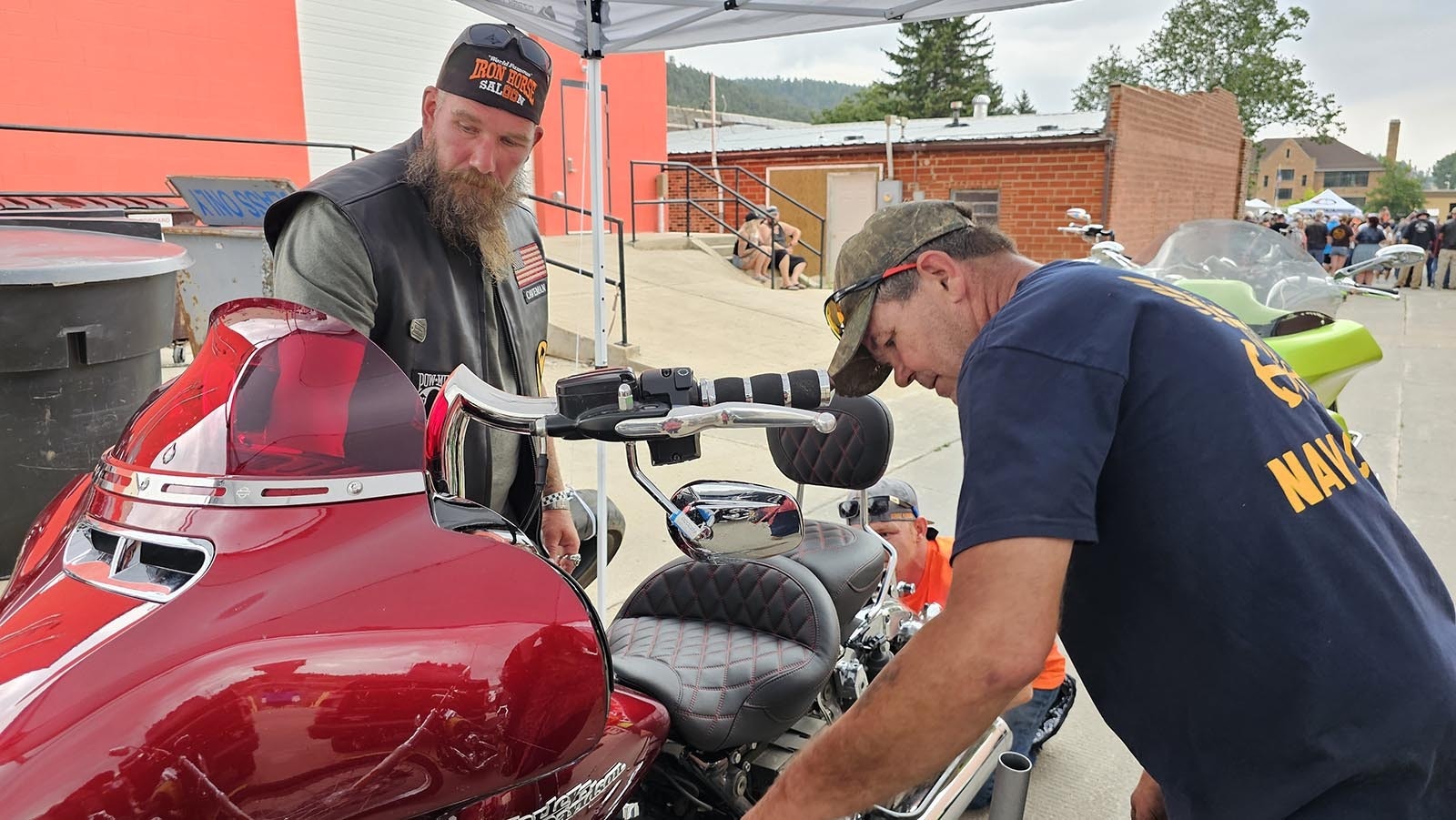 Cory Rand, left, helps replace the tire on his bike with a used one before the Burnout.