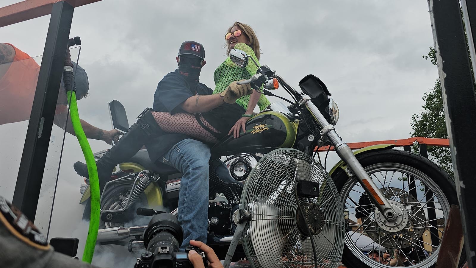 Jess Jones, with her husband Casey, smiles down at the crowd just before the couple's burnout exhibition ride in Sundance.