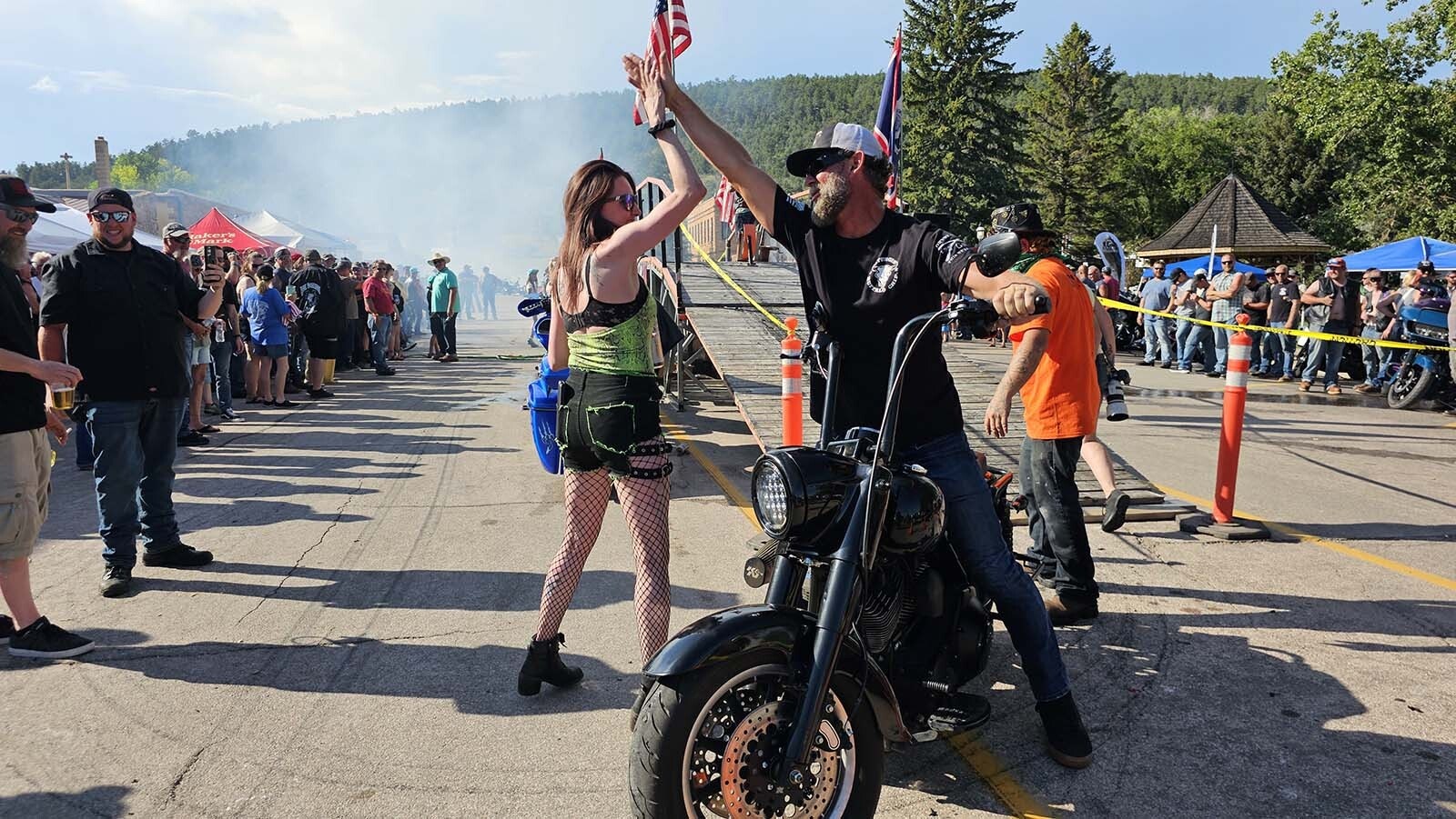 Dime Horseshoe bar owner Jess Jones high-fives a biker after his burnout ride.