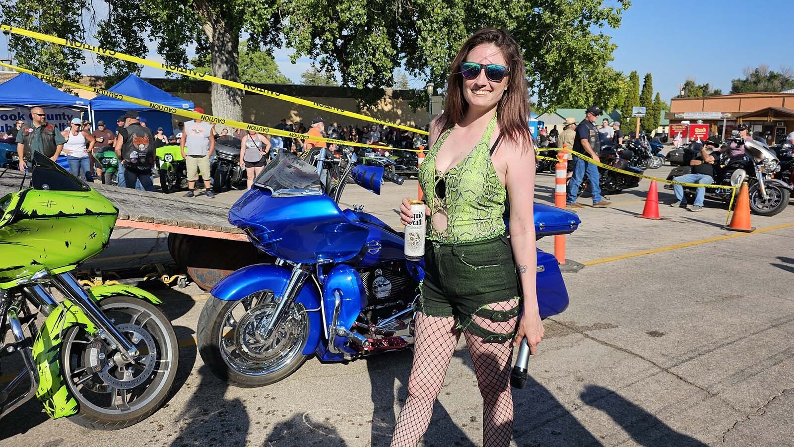 Dime Horseshoe Bar owner Jess Jones pauses for Cowboy State Daily a moment  and strikes a smiling pose for this photo at the 50th anniversary of the Sundance Burnout during the Sturgis Motorcycle Rally.