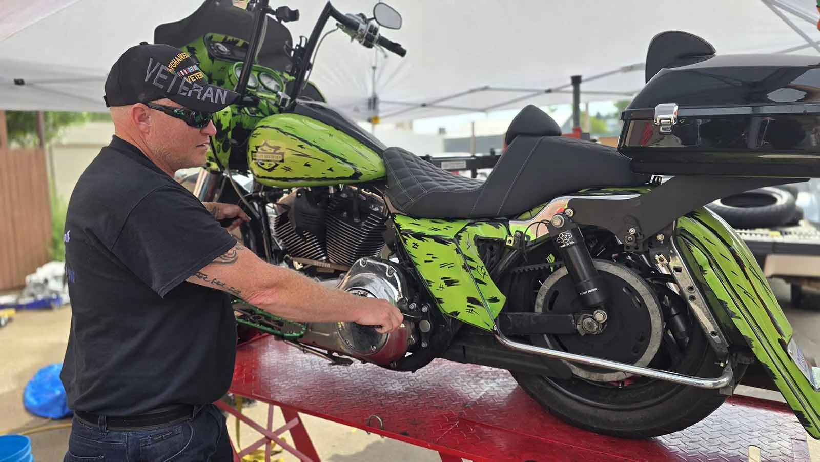 Bill Snider holds is bike while mechanics work to remove its good tire and swap in a used tire for the Dime Horseshoe Bar's annual Burnout in Sundance.