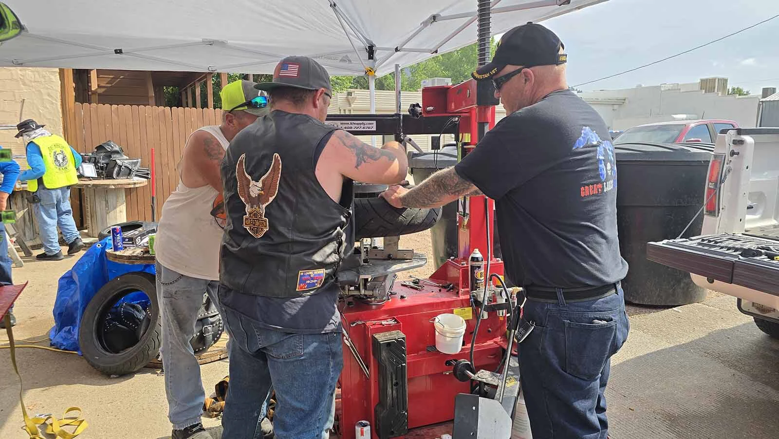 Bill Snider helps mechanics as they work to swap in a used tire for his good one during the Dime Horseshoe Bar's annual burnout in Sundance during the Sturgis Rally.
