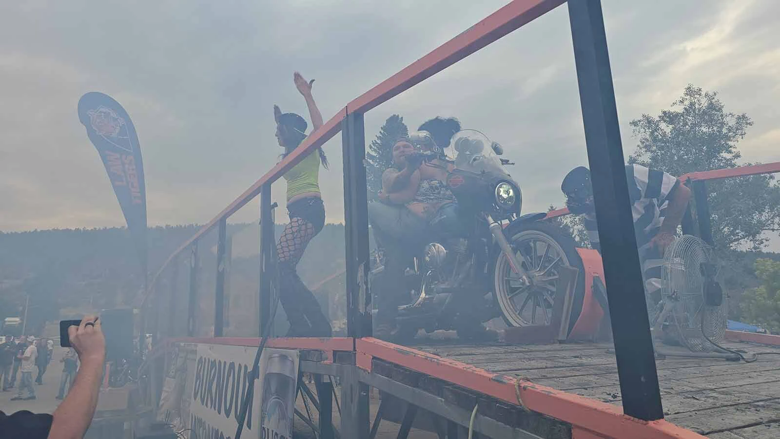 Dime Horseshoe Bar owner Jess Jones urges the crowd to cheer during a burnout ride in Sundance. The contest is held every year during Sturgis Rally week.