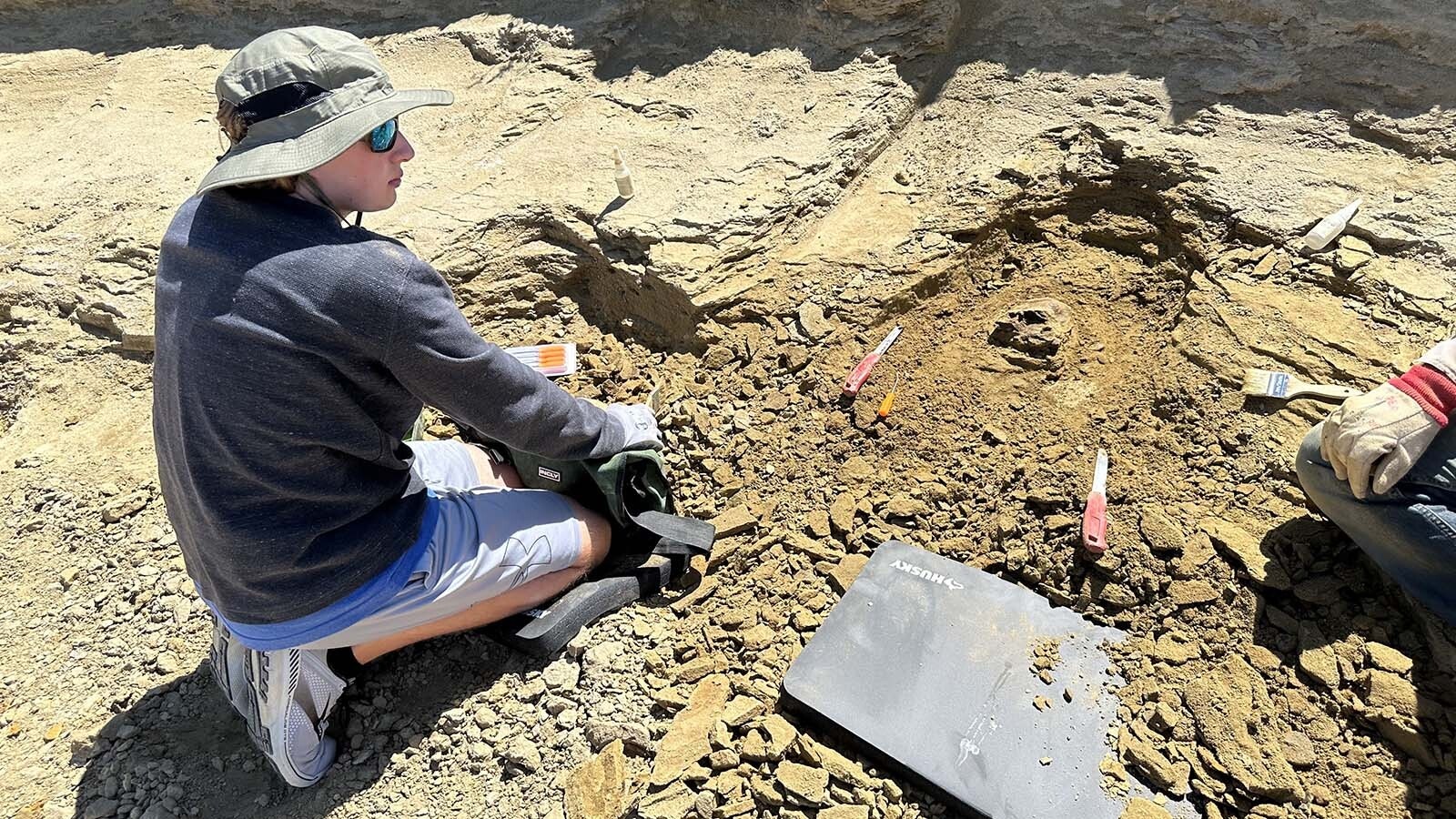Chase Blanchard working on a large Edmontosaurus foot bone he and his father Ted discovered, with guidance from Kemmerer Mayor Robert Bowen at a site in eastern Wyoming.