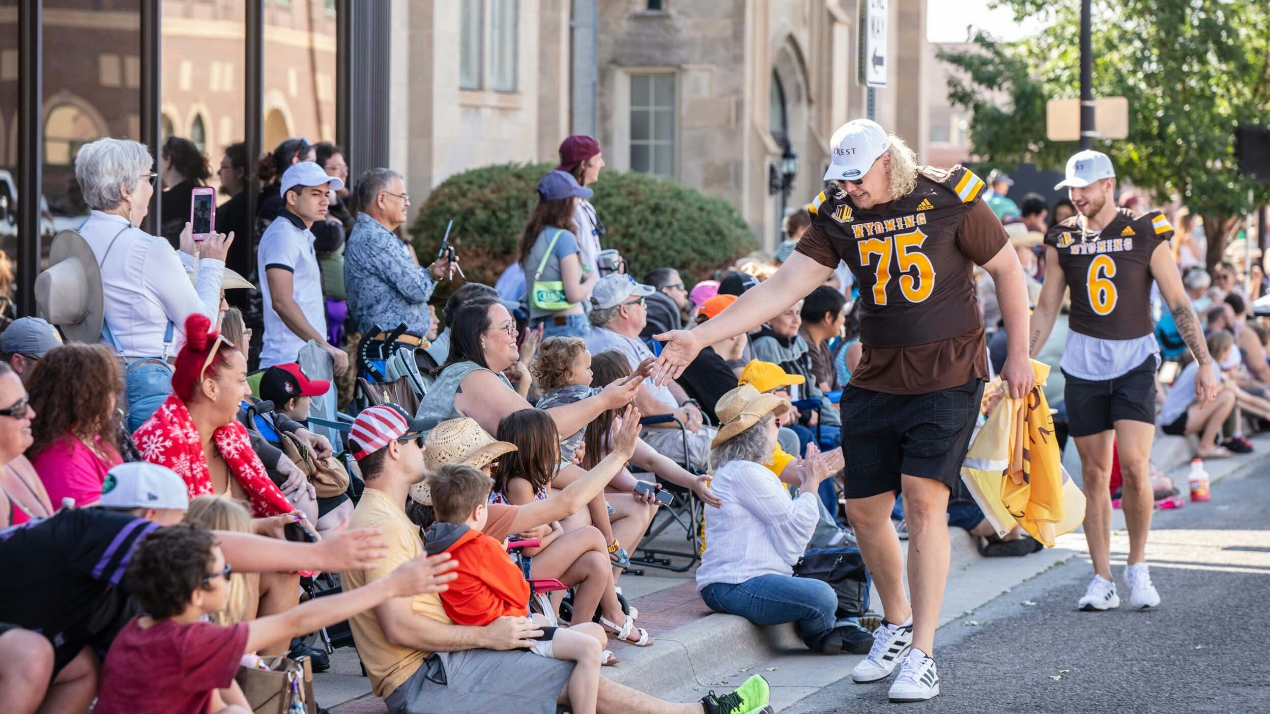 University of Wyoming Football Players, Frank Crum and Andrew Peasley high-five parade watchers at the Cheyenne Frontier Days Parade on July 29, 2023 in downtown Cheyenne.