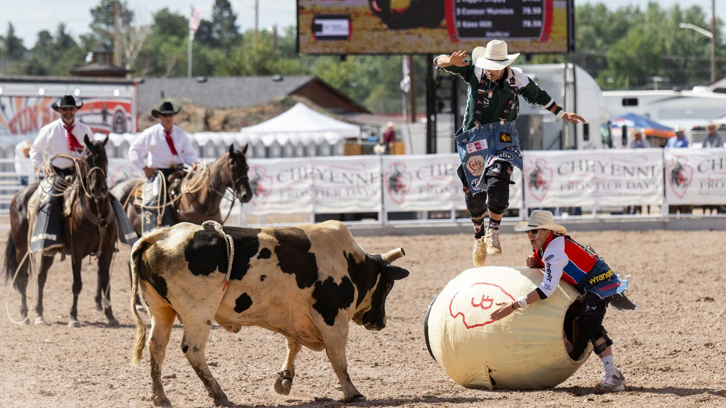 Bull Fighters Dusty Tuckness and Cody Webster fight a bull while Barrelman Cody Sosebee hides in the barrel at Cheyenne Frontier Days on July 25, 2023.