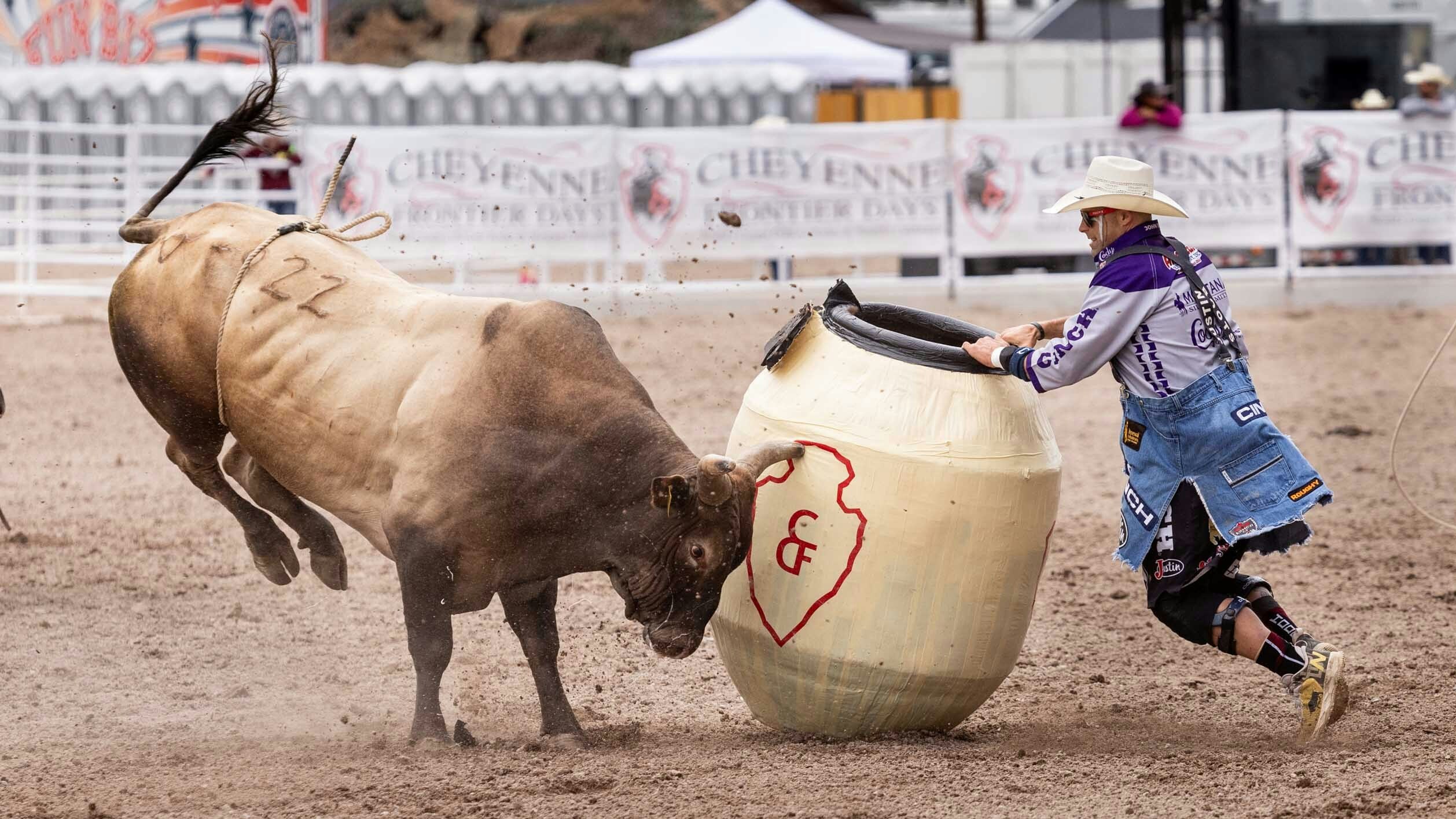 Bullfighter Dusty Tackness from Meeteetse, Wyoming fights a bull during the bull riding at Cheyenne Frontier Days on July 23, 2023.