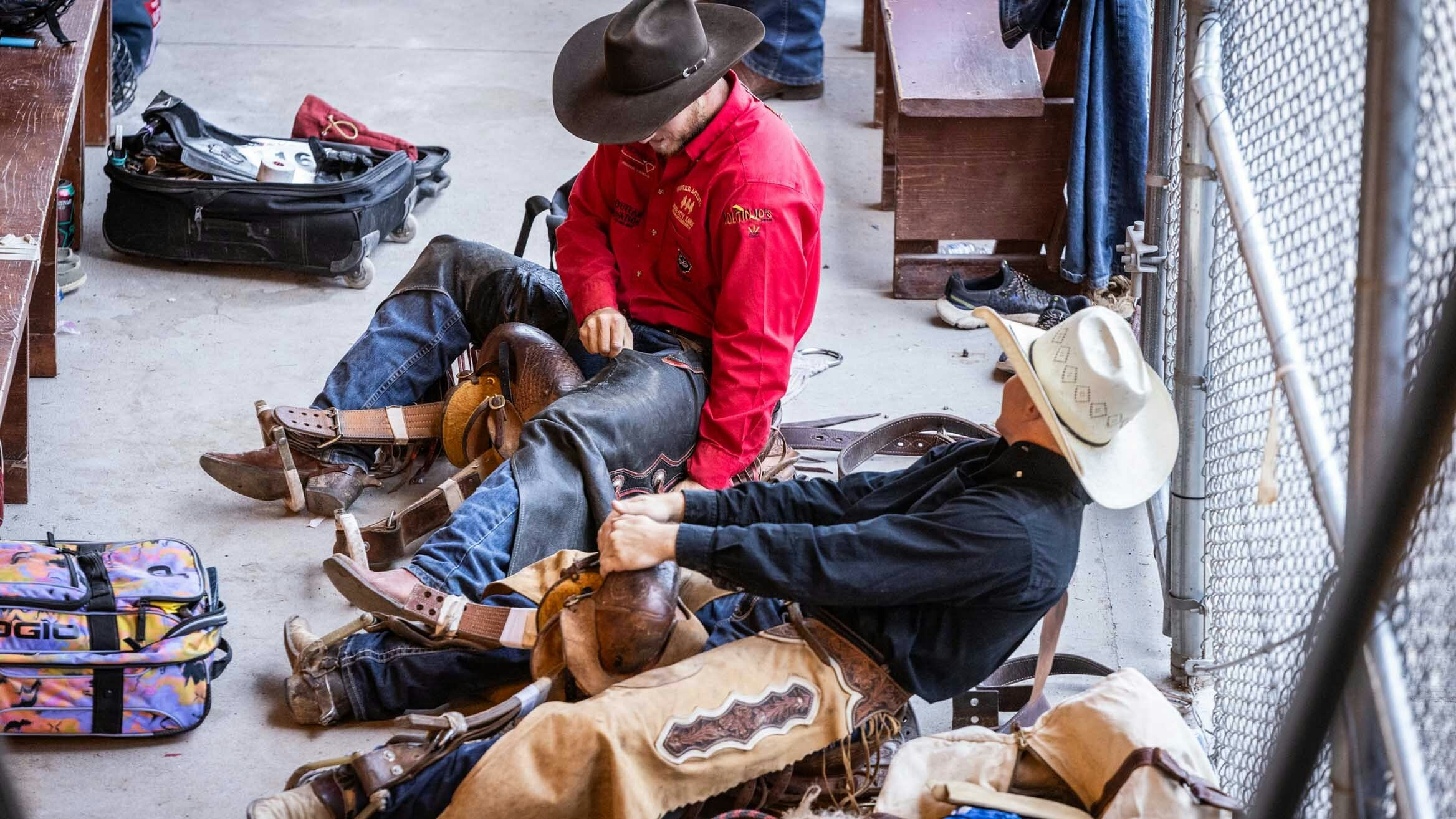 Saddle bronc riders get ready for their bronc ride in the ready area behind the chutes at Cheyenne Frontier Days on July 24, 2023.
