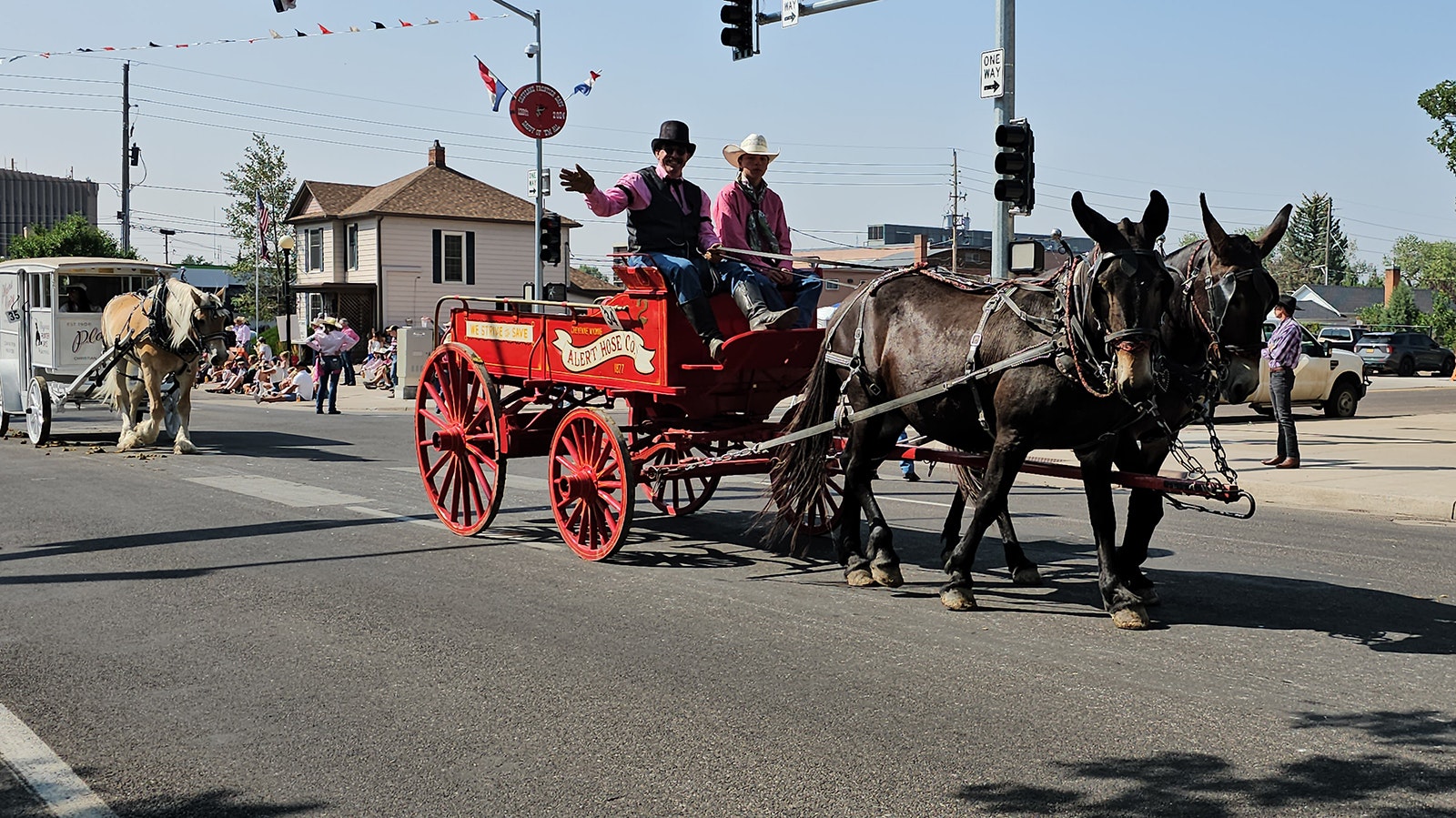 Sam Gill waves at the crowd and he drives a team of horses pulling a fire engine wagon in the Cheyenne Frontier Days annual parade.