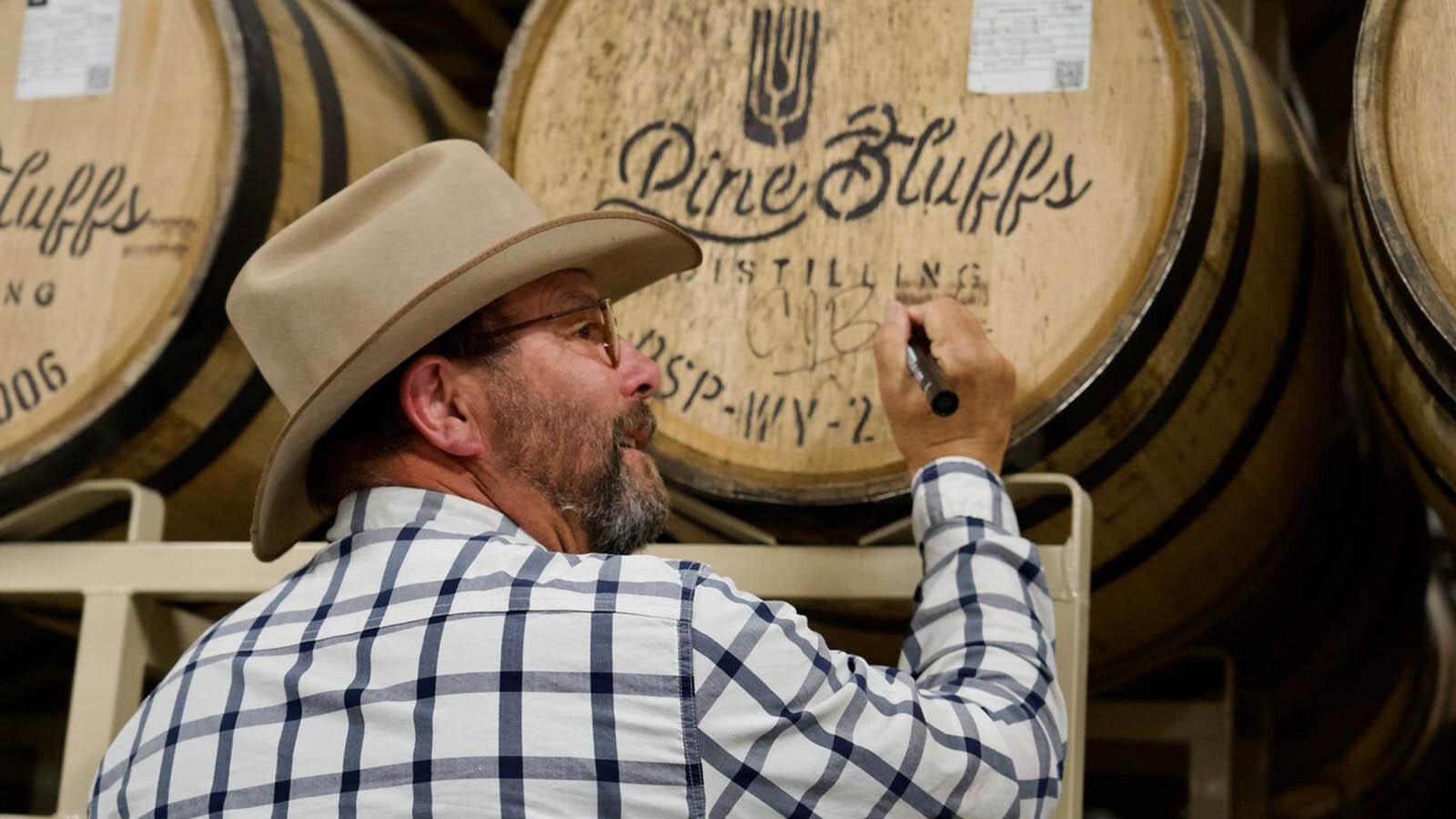 C.J. Box signs a barrel of bourbon at Pine Bluffs Distilling. The distillery will create a Joe Pickett bourbon for release in 2025.