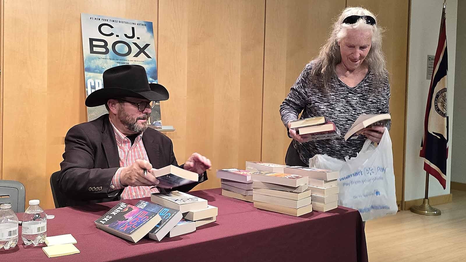 C.J. Box pauses book signing for a moment to watch Dianne Stoutenburg as she pulls more books out of a grocery bag.