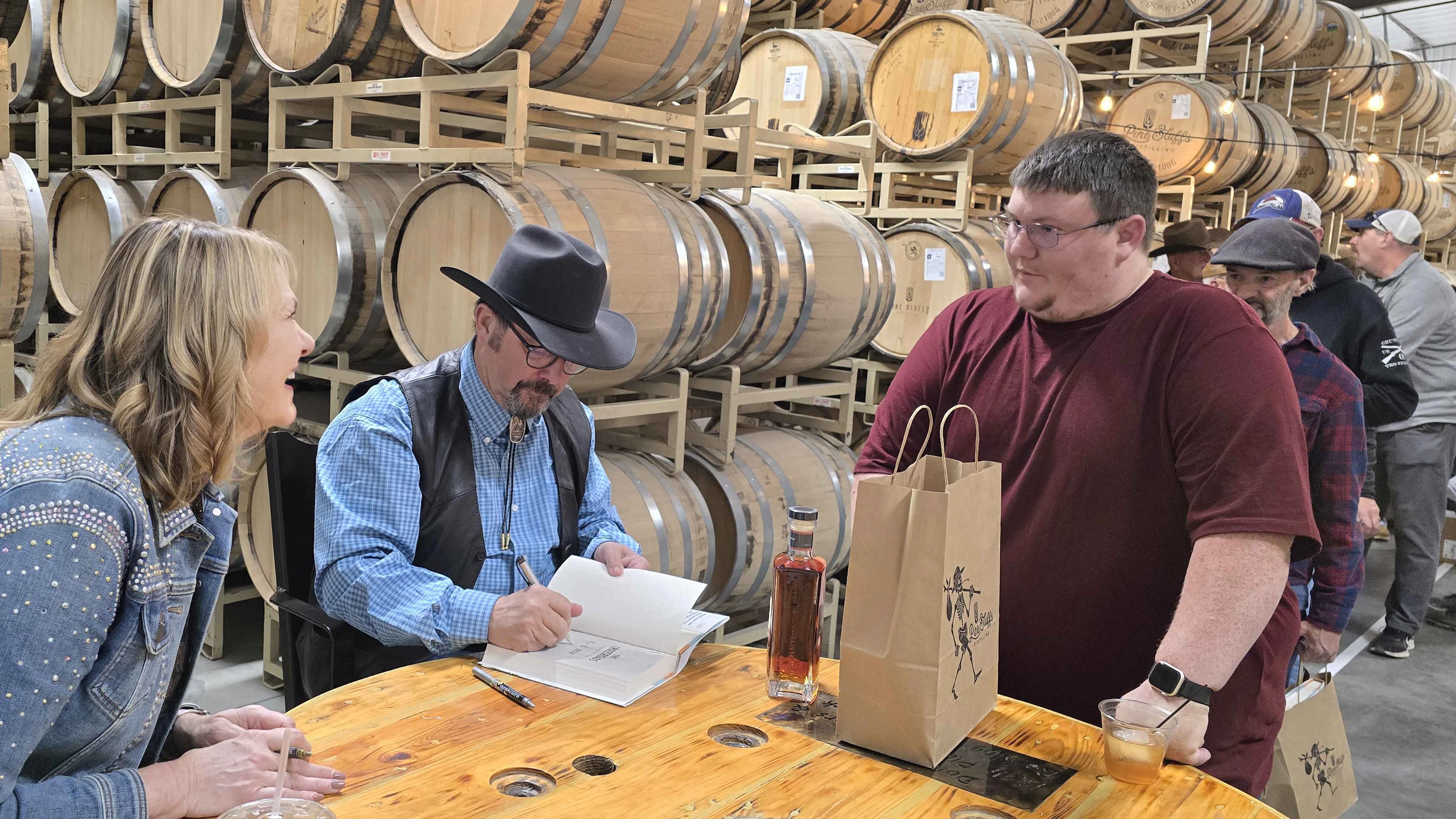 Keegan Dix gets both a book and his bottle of Romanowski Rye signed at Pine Bluffs Distilling on Saturday.