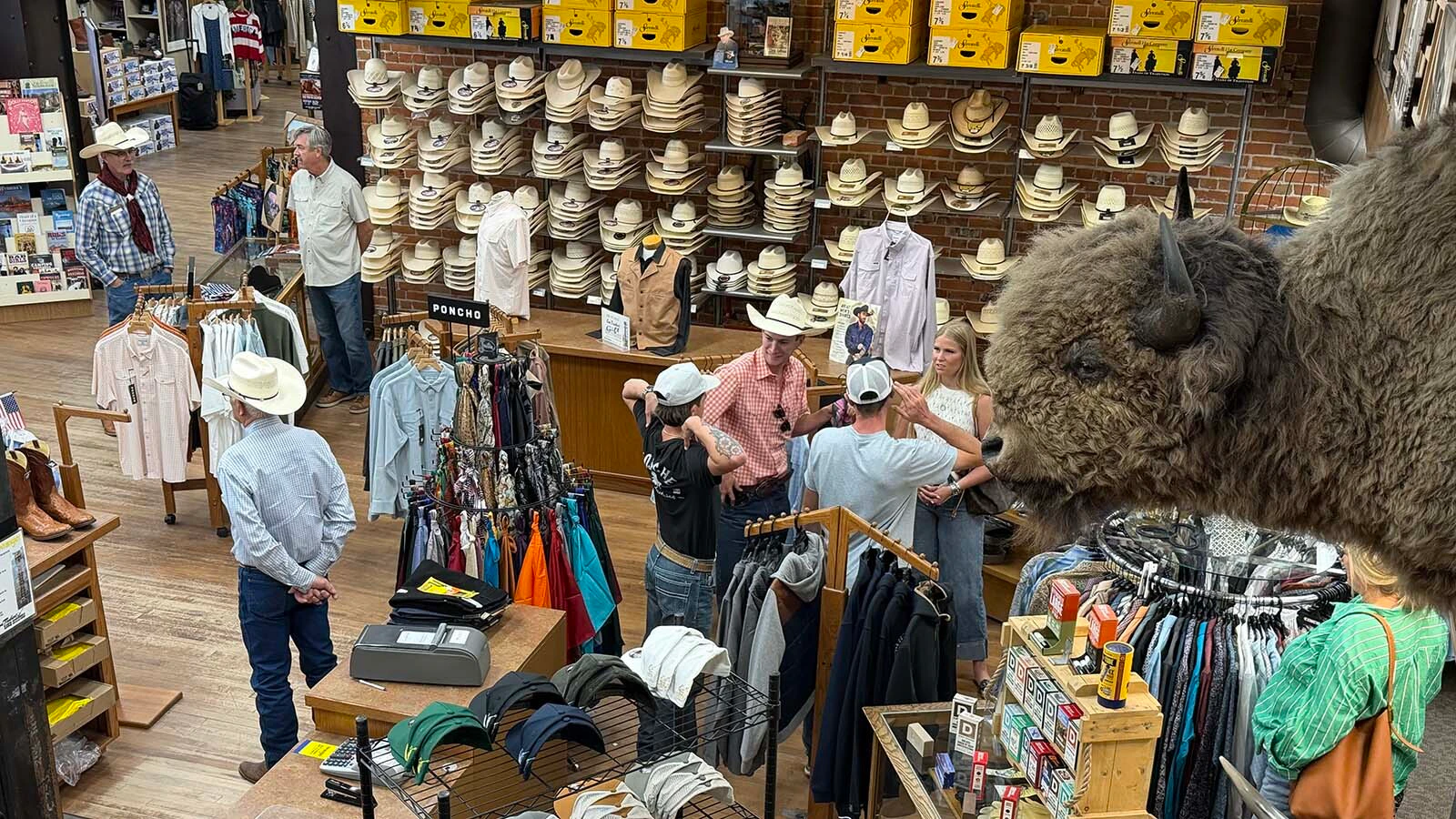 Customers browse beneath rows of cowboy hats at Lou Taubert Ranch Outfitters during the College National Finals Rodeo.