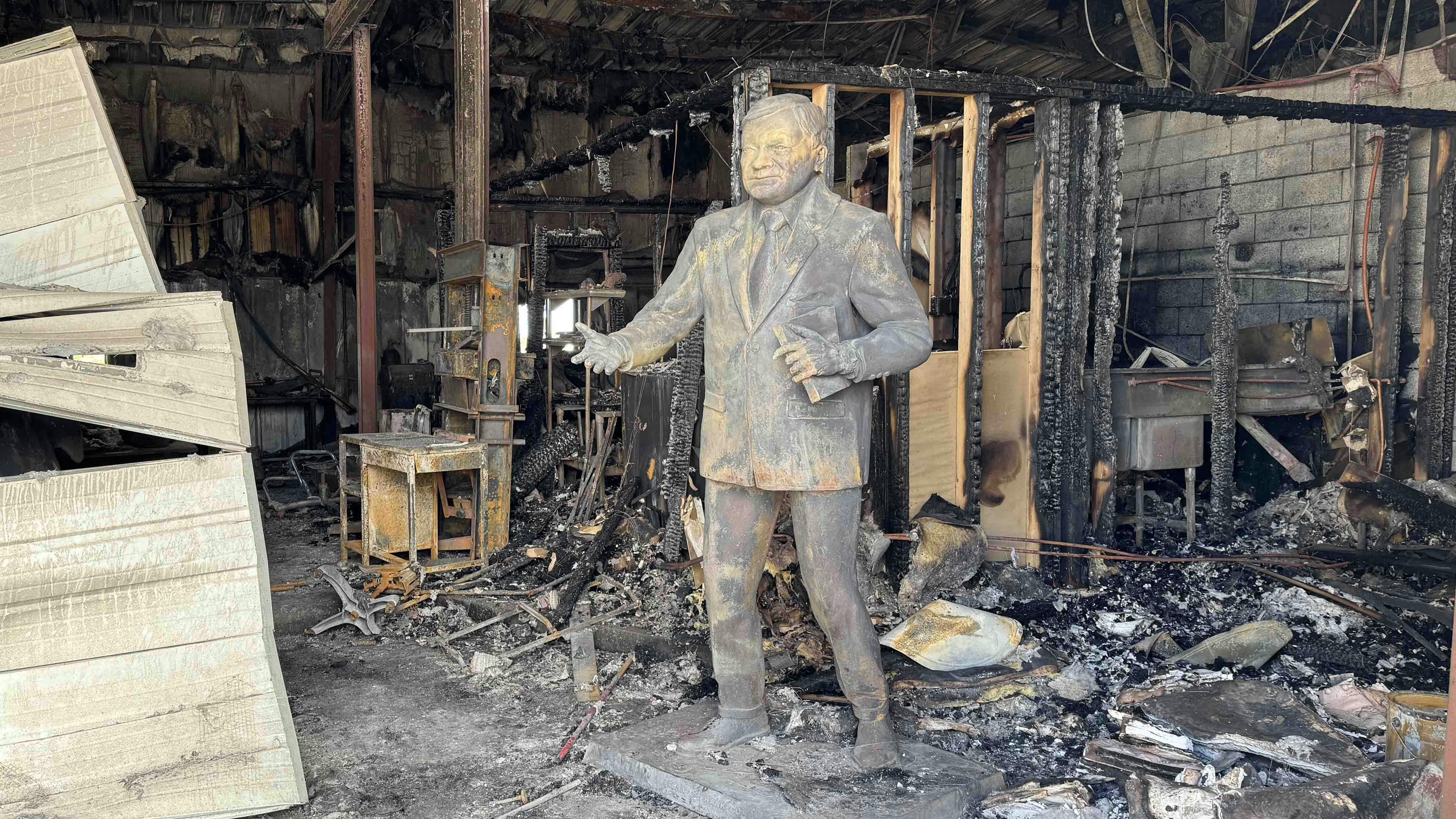 A bronze statue of Wyoming State Senator Hank Coe stands amid the charred remains of the Calceo Foundry. The cause of the overnight fire that destroyed everything inside is under investigation.