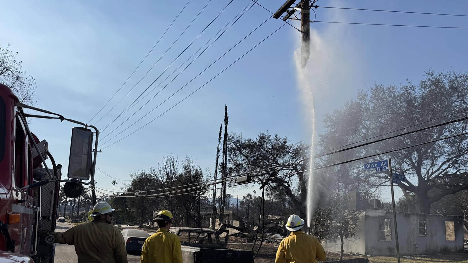 A crew from the Fremont County Fire Protection District hoses down a burned telephone pole in Southern California.