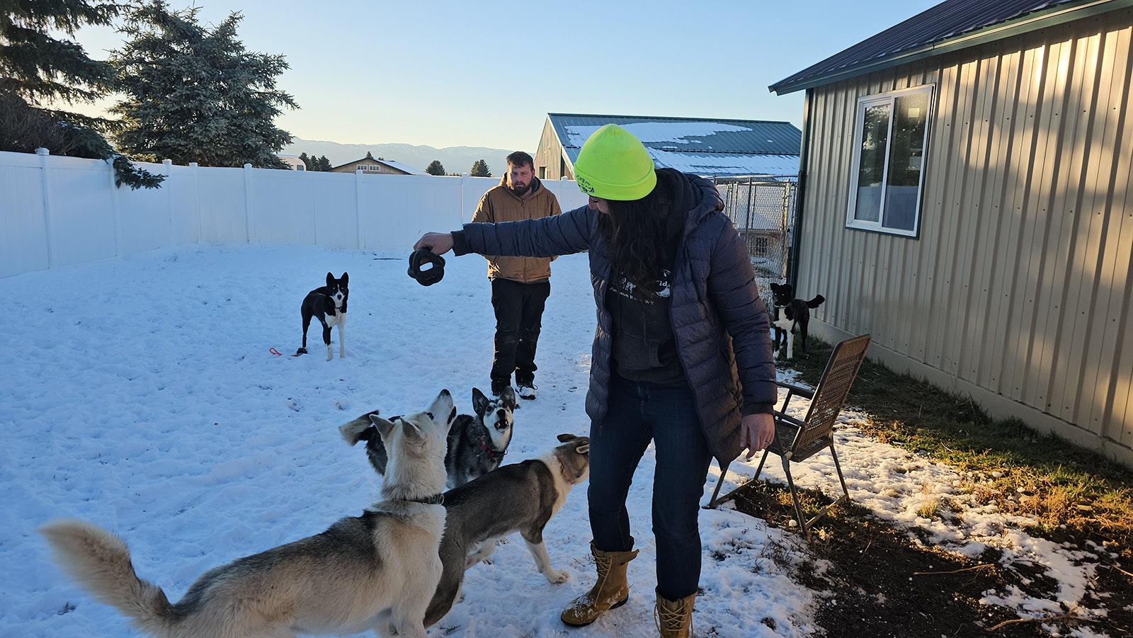 Abby Tarver gets ready to throw a fun chew toy for some of her huskies, while Michael Tarver looks on in the background. The two own the Call of the Wyld dog sledding tour business in Jackson Hole.