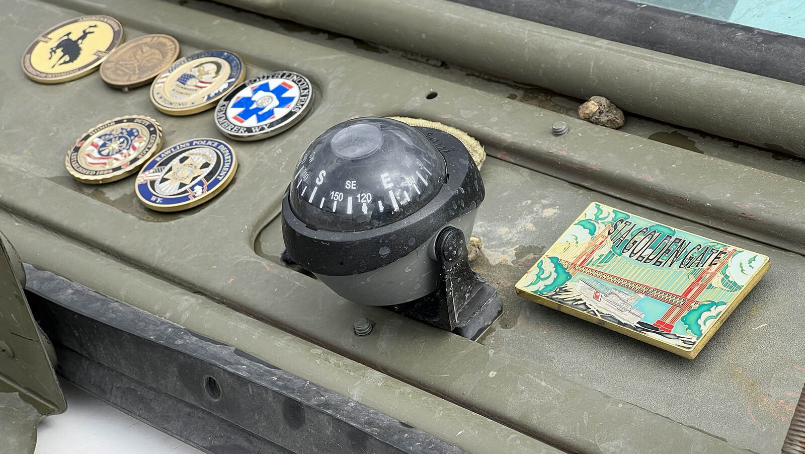 The dash of the 1952 Willys Jeep displays the military coins from various stops along its cross-country trip, starting at the Golden Gate Bridge.