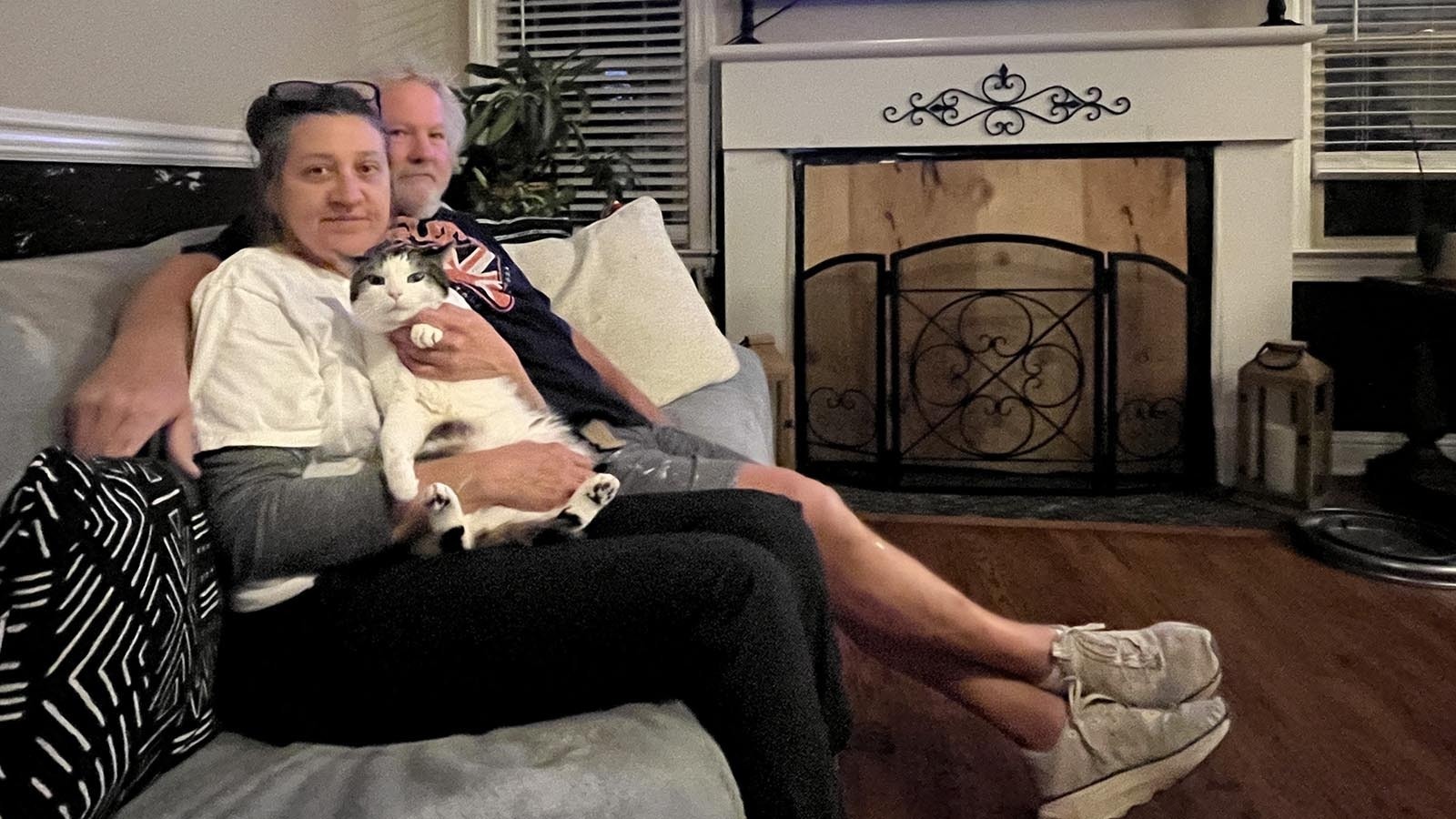 Susie Degner and Bill Lembke, and their cat Joey, hang out in their living room that was breached by a car last month.