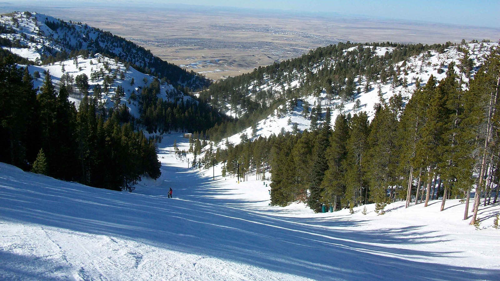 View down a run at Hogadon Basin Ski Area with the city of Casper visible in the distance.