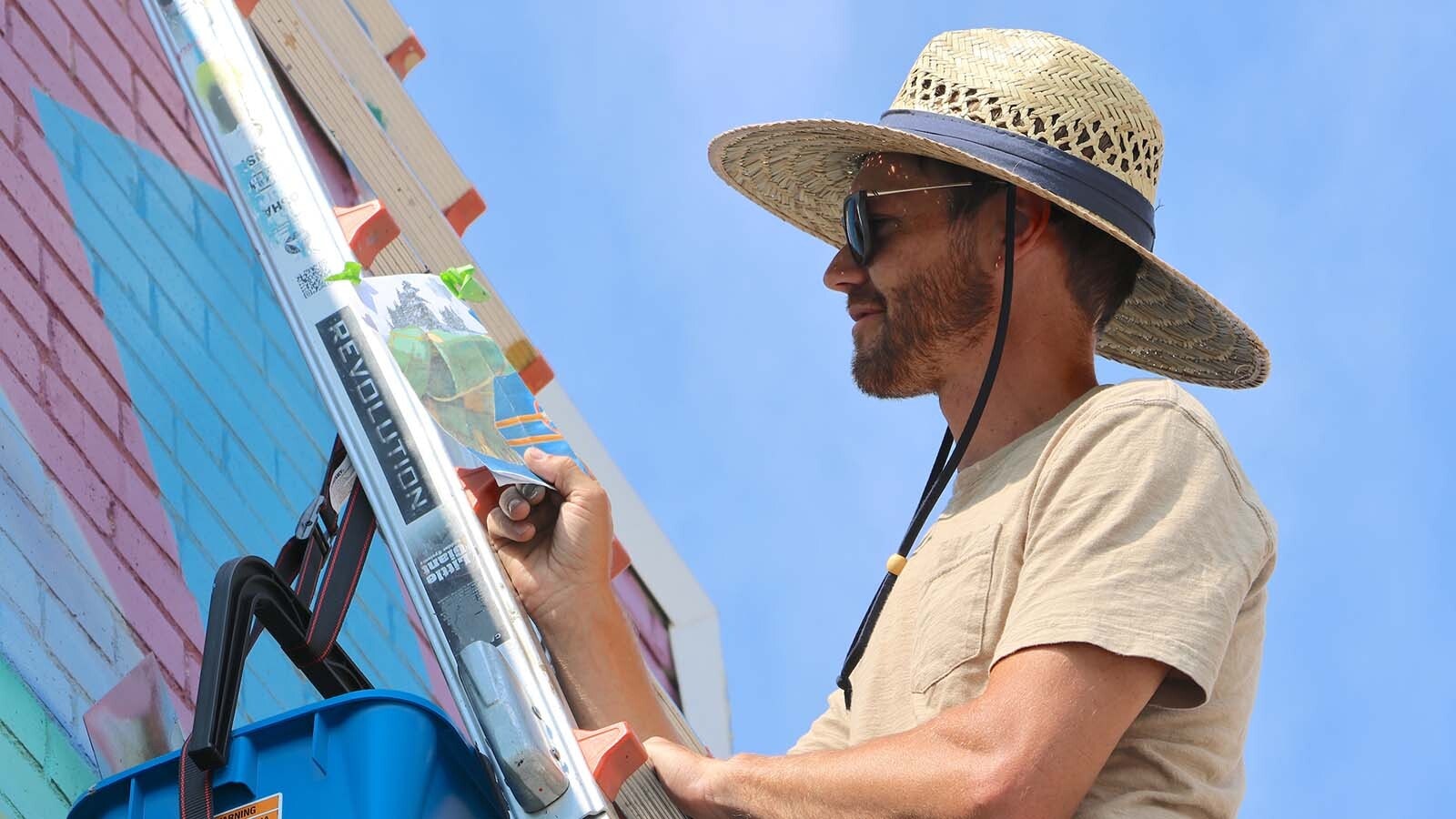 Artist Dan Toro keeps a portion of the mural section depicted on art paper with him as he paints on the wall.