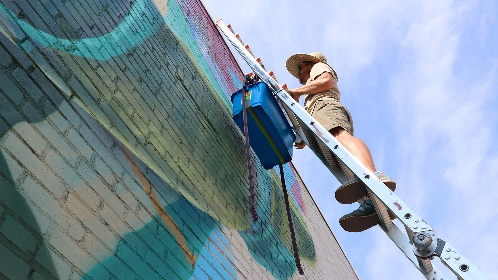 Artist Dan Toro stands at the top of his 22-foot ladder. He said working near the roof line and getting things right is one of the harder aspects of the mural.