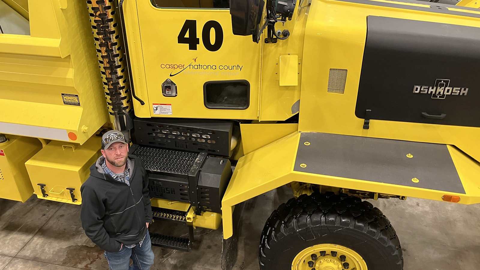 Deputy Director for Construction and Maintenance Jake Hlavacek stands next to the plow and deicer truck that can carry pellets and liquid deicer for the runways.