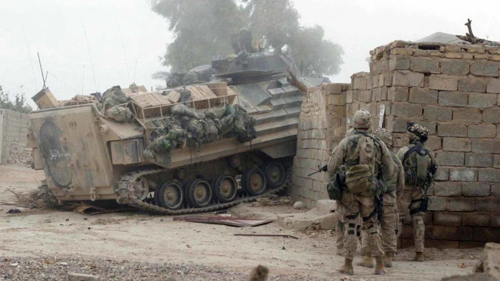 An amphibious assault vehicle drives through a wall and locked gate to open a path for Marines in the 2nd Platoon, India Company, 3rd Battalion, 1st Marines in Fallujah in November 2004.