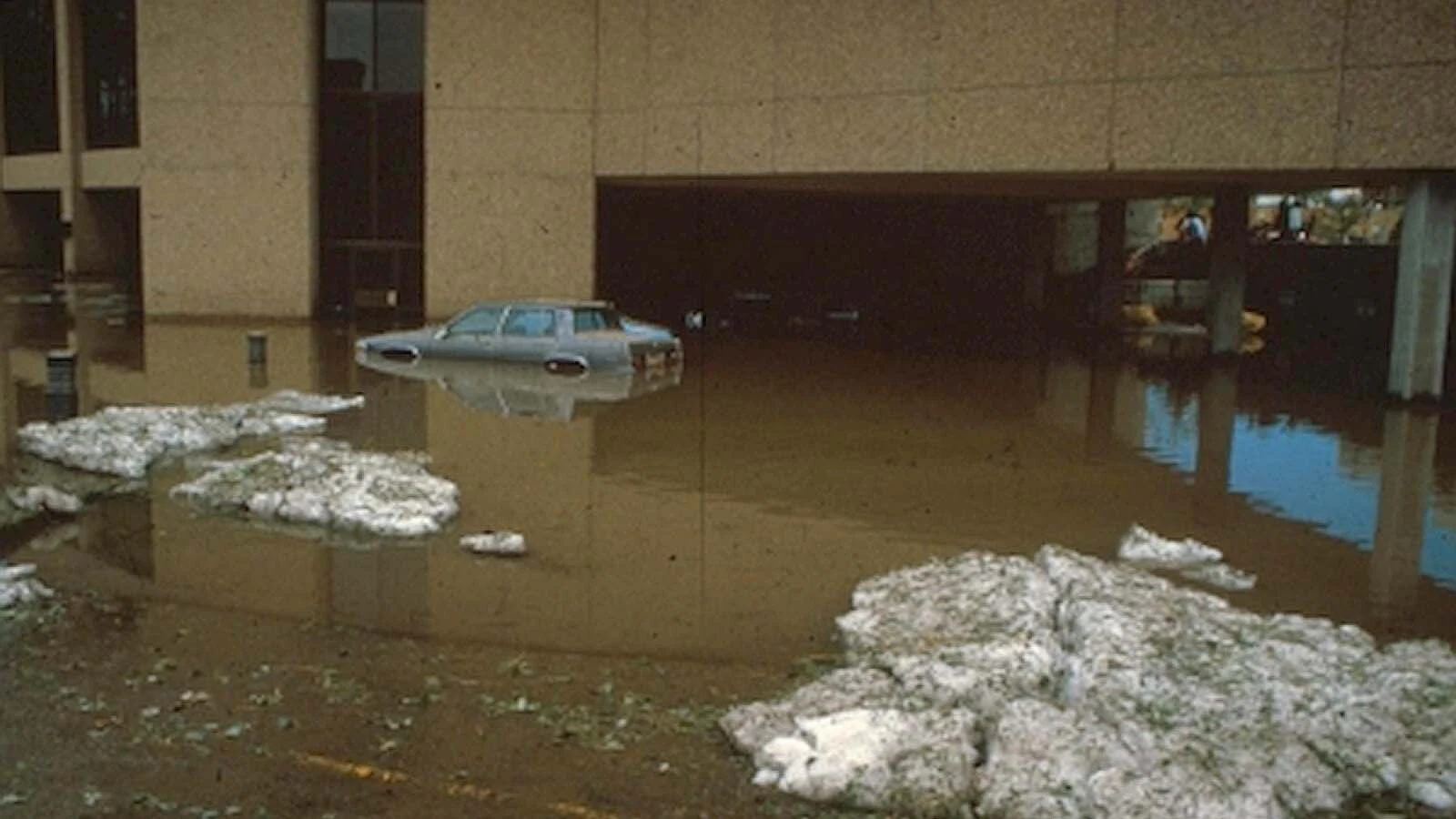 A car submerged in flood waters with drifts of hail in front of Cheyenne Bank on Aug. 1, 1985.