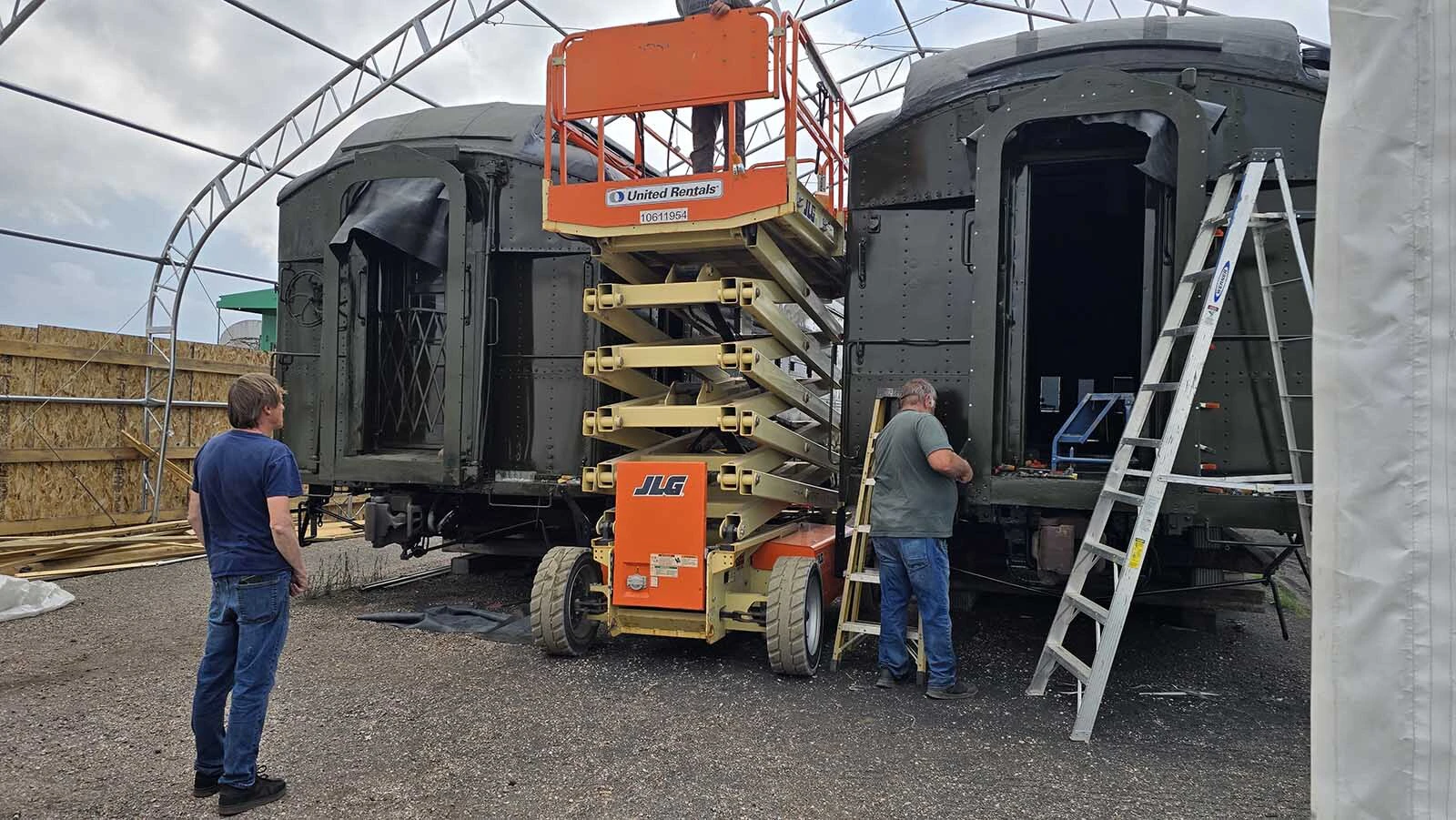 Mike Pannell, left, watches as a member of his train restoration crew slowly moves a scissors lift from in between two railcars that are being restored for Cheyenne's 15th Street Railcar Experience.