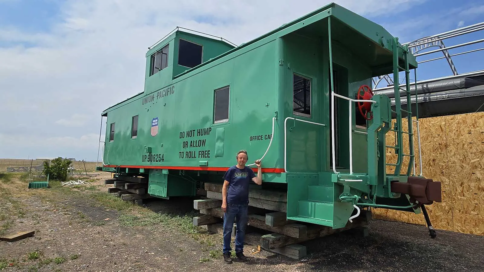 Mike Pannell, president of High Plains Railroad Preservation Association, stands beside the caboose his nonprofit restored for Cheyenne's 15th Street Railcar experience.