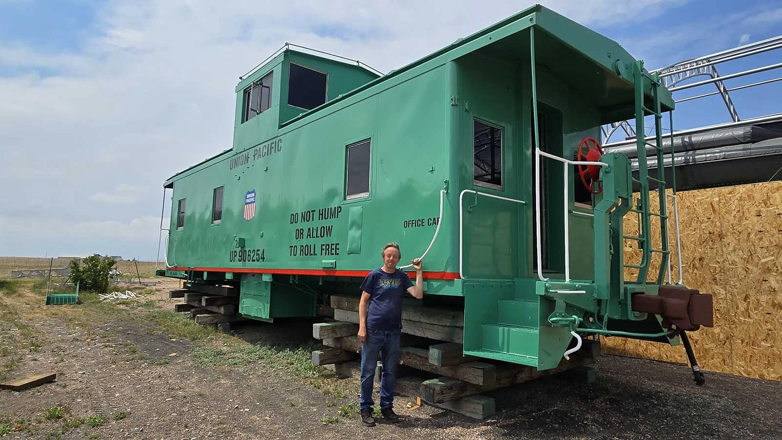 Mike Pannell, president of High Plains Railroad Preservation Association, stands beside the caboose his nonprofit restored for Cheyenne's 15th Street Railcar experience.