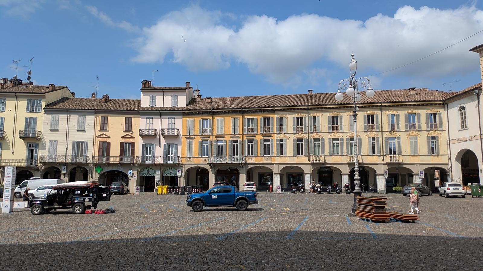 The main square in Voghera's city center features small porticos and four staples: municipal buildings, the cathedral, a pharmacy, and a doctor's office.