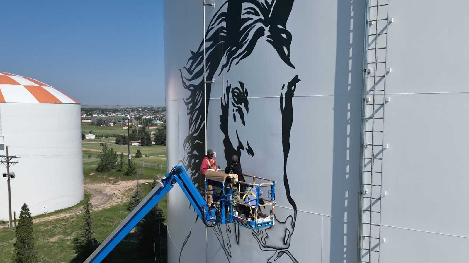 Cheyenne artist Jordan Dean is painting two giant 60-to-70-foot horses as the centerpiece of a stunning mural on a prominent water tank. It takes two giant booms, a projector and $400 a gallon paint.