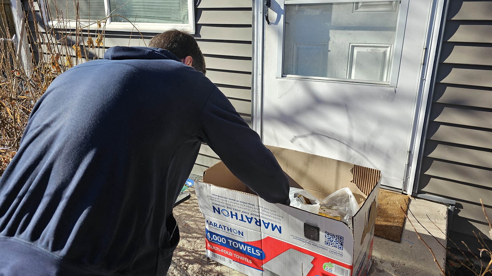 Landyn Medina tucks a 20 bill into a box of food he's leaving for a Cheyenne family whose home was inundated with floodwaters in the Cahill Park area.