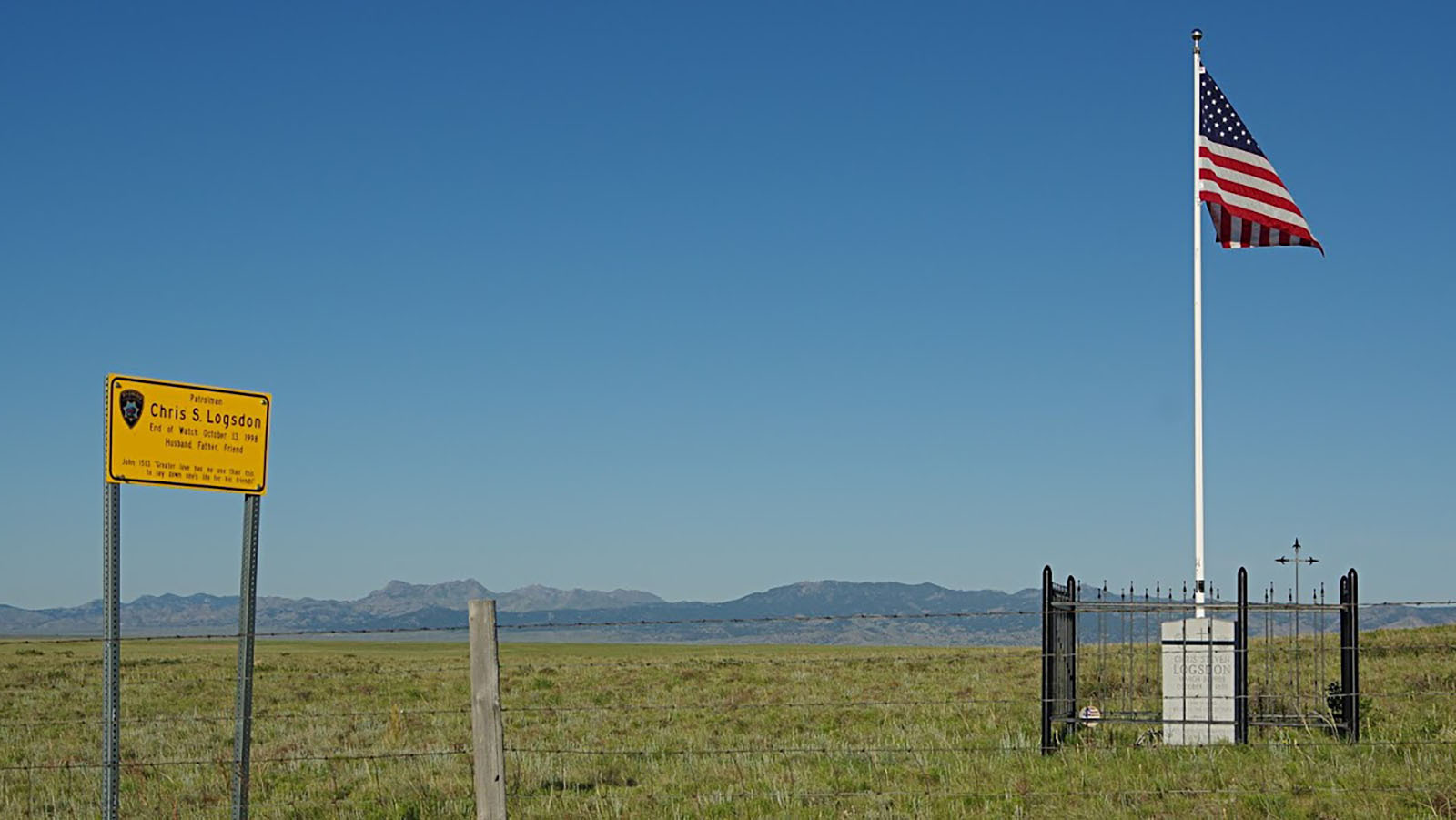 A sign, marker and flag memorialize Wyoming Highway Patrol Trooper Chris Logsdon, who was killed Oct. 13, 1998, in a crash while responding to a wrong-way driver on Interstate 25 near Wheatland, Wyoming.
