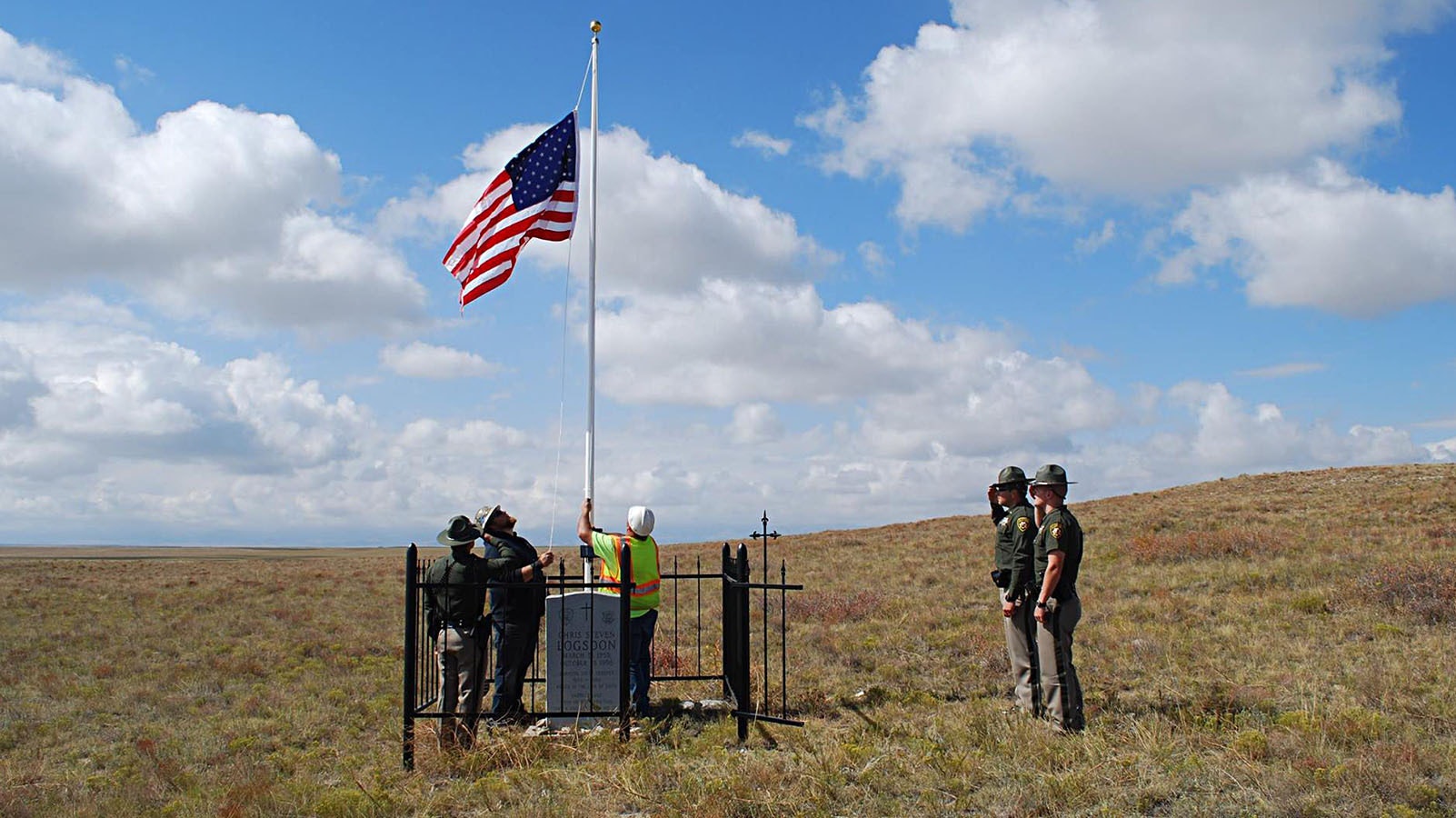 Troopers salute after changing the flag at a marker memorializing the active-duty death of Trooper Chris Logsdon off I-25 near Wheatland, Wyoming.