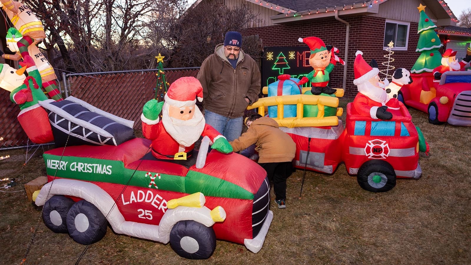 Carsen and Brian Bartow check and straighten up inflatable decorations to ensure everything is ready for Christmas light display viewers in Cheyenne, Wyoming.