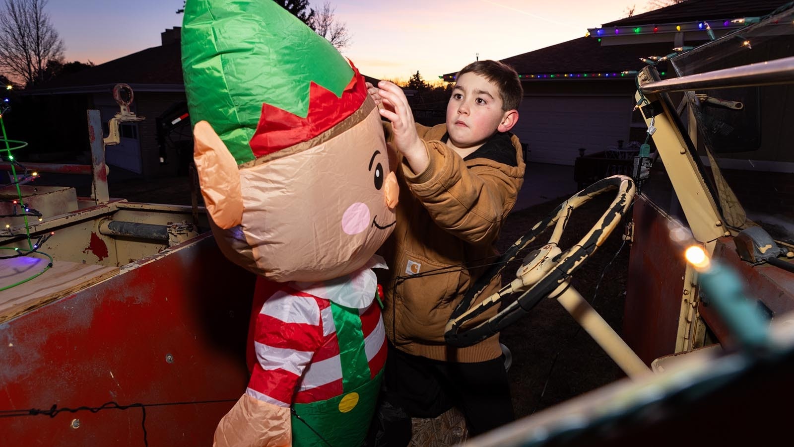 Carsen Bartow puts inflatable Christmas decorations in place. The display is all about Santa and fire trucks.