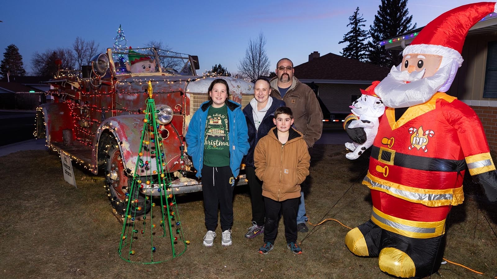 Paige, Brittney, Carsen, and Brian Bartow stand in front of their decorated 1942 LaFrance fire truck all decked out for Christmas in Cheyenne, Wyoming.