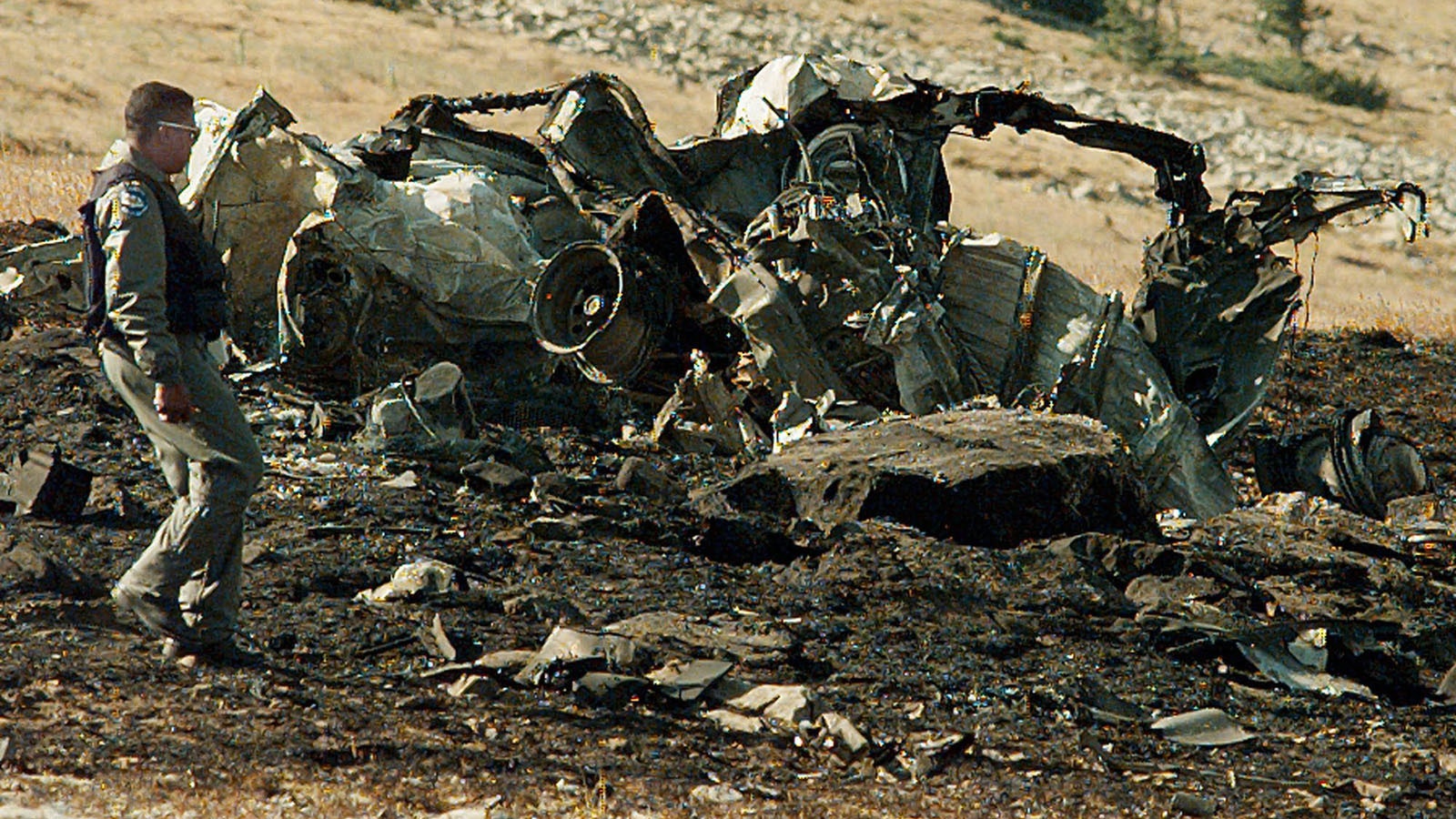 A investigator walks past the burned wreckage of the Secret Service communication vehicle that was on board the Air Force C-130 that crashed and burned on a mountain near Jackson, Wyoming on Aug. 17, 1996.  The C-130 carried support equipment for President Clinton's vacation. Nine people were killed, including a Secret Service agent.