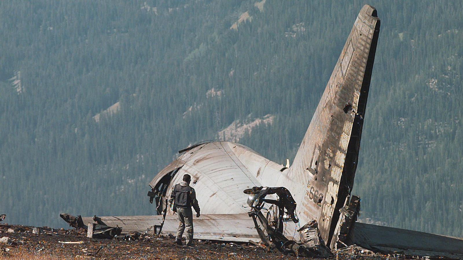 A member of the Air Force crash investigation team surveys the tail section of the Air Force C-130 that crashed and burned near the top of Sheep Mountain near Jackson, Wyoming, on Tuesday, Aug. 20, 1996. The C-130, which carried support equipment for President Clinton's vacation, went down on takeoff late Saturday night. Nine people were killed in the crash.