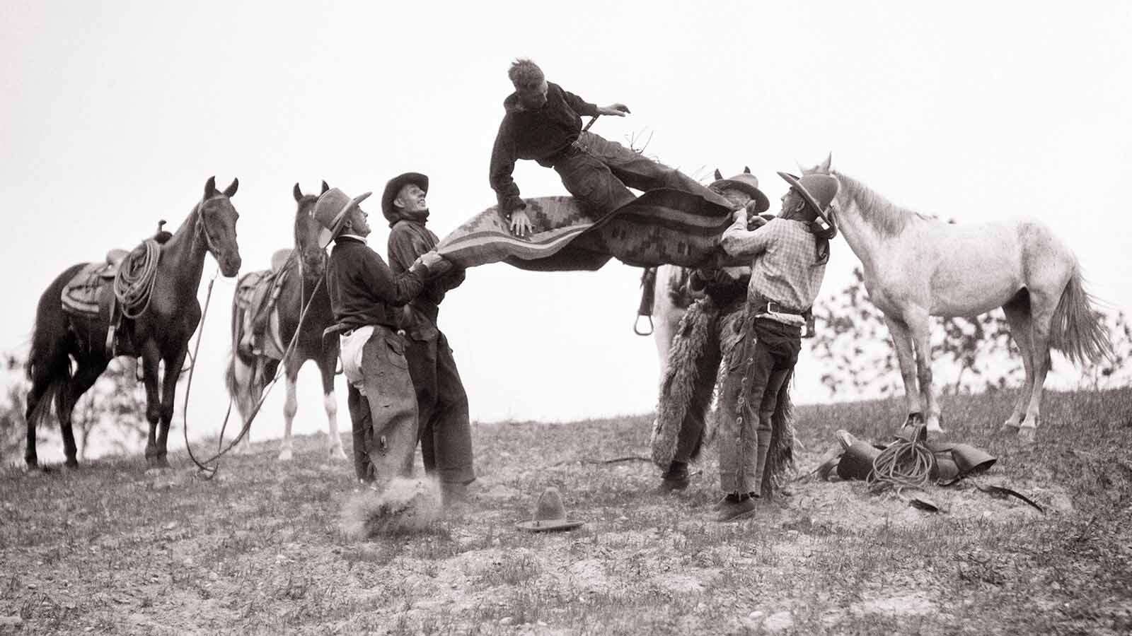 A group of cowboys in the 1920s blow off some steam by tossing each other in a blanket.