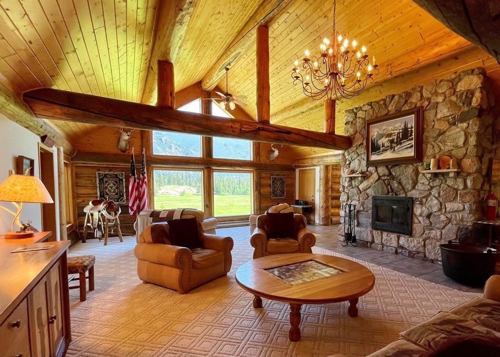 A large rock fireplace and whole-log beams sets the tone for the living room area.