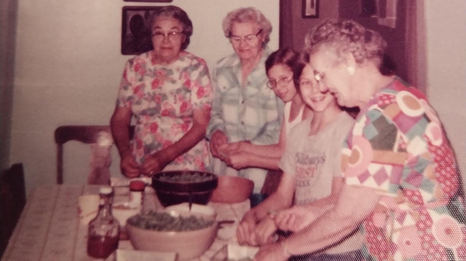 A photo shows Mary Akers, second from left, Glenda Wiken’s grandmother, and Diane Downey as a girl, second from right, canning green beans.