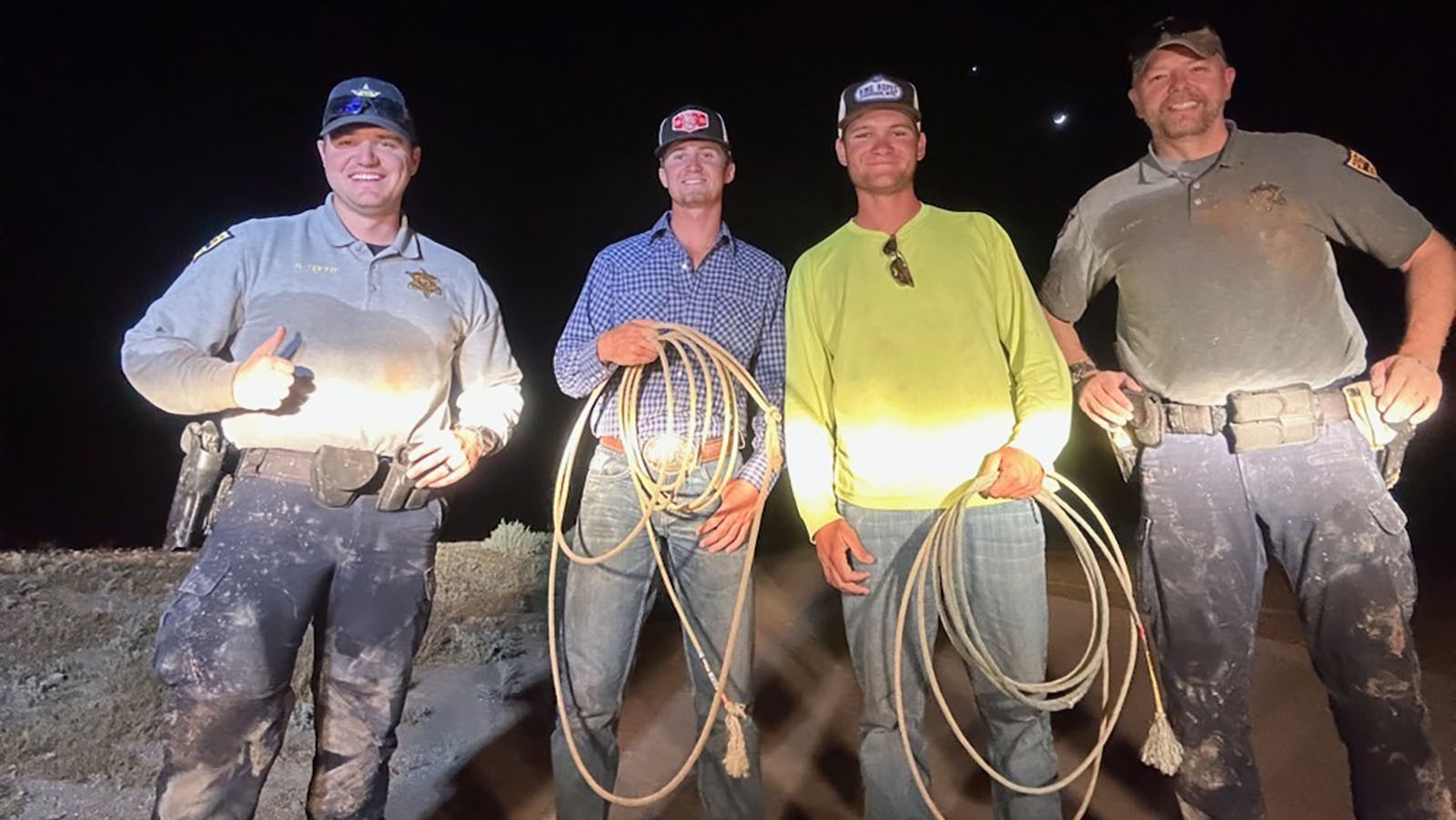 Arizona wildlife officials with two cowboys who helped wrangle a pair of mule deer stuck in a canal.