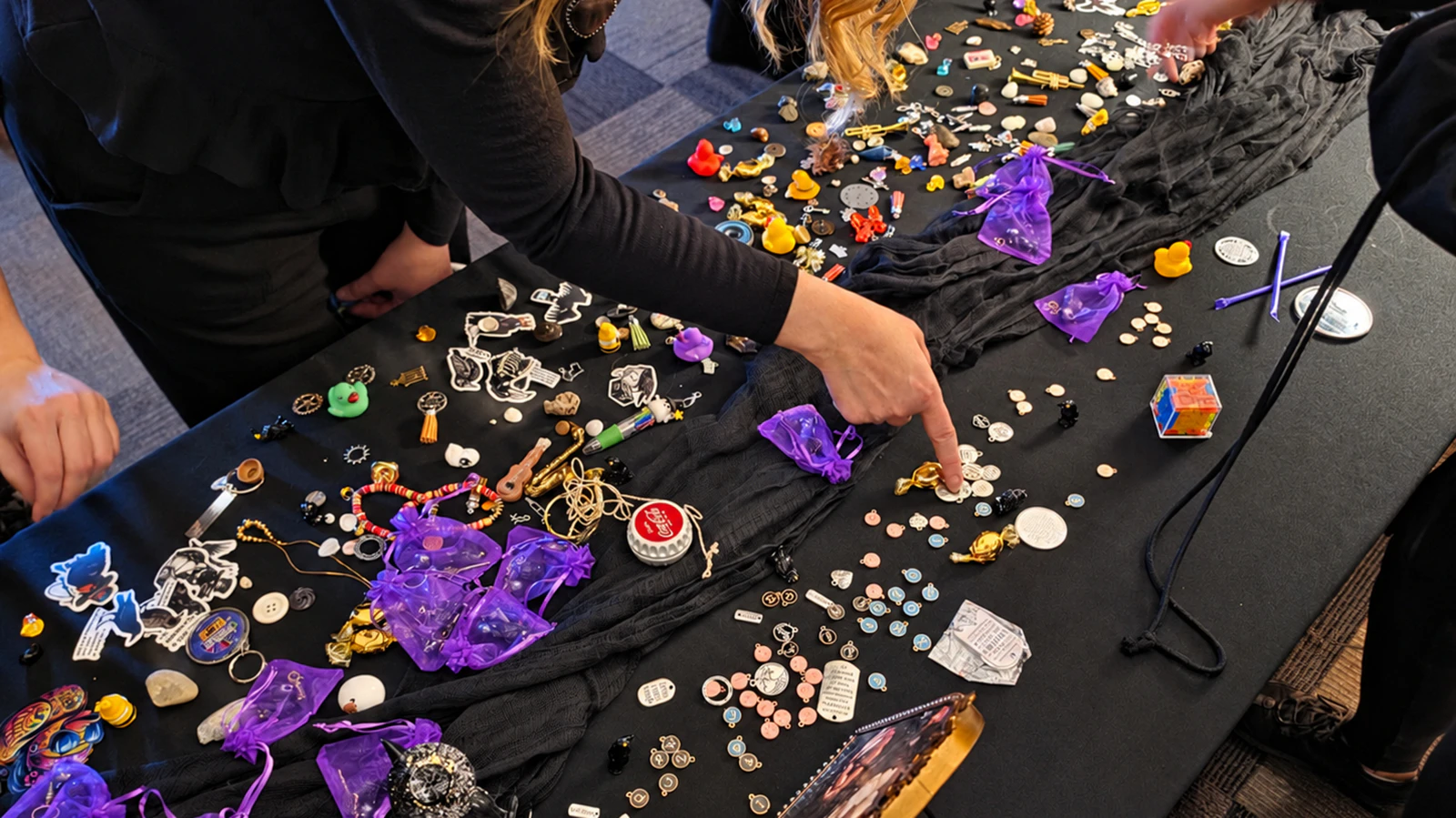 Attendees pick through a table covered with buttons, charms, coins, jewelry, rocks and other small treasures.