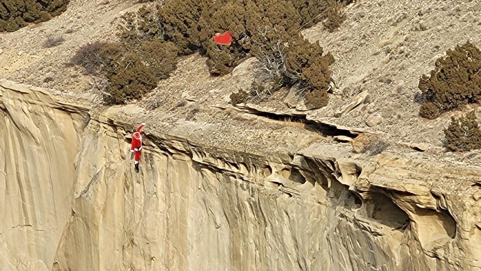 Santa dangles precariously from a cliff some where in Wyoming, prompting Fred Lowry to observe that "even the most experienced drivers can run into trouble in the Wyoming mountains!"